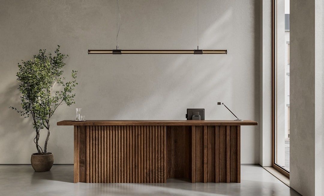 Minimalistischer Empfangstresen aus Holz mit Pflanze und Pendelleuchte